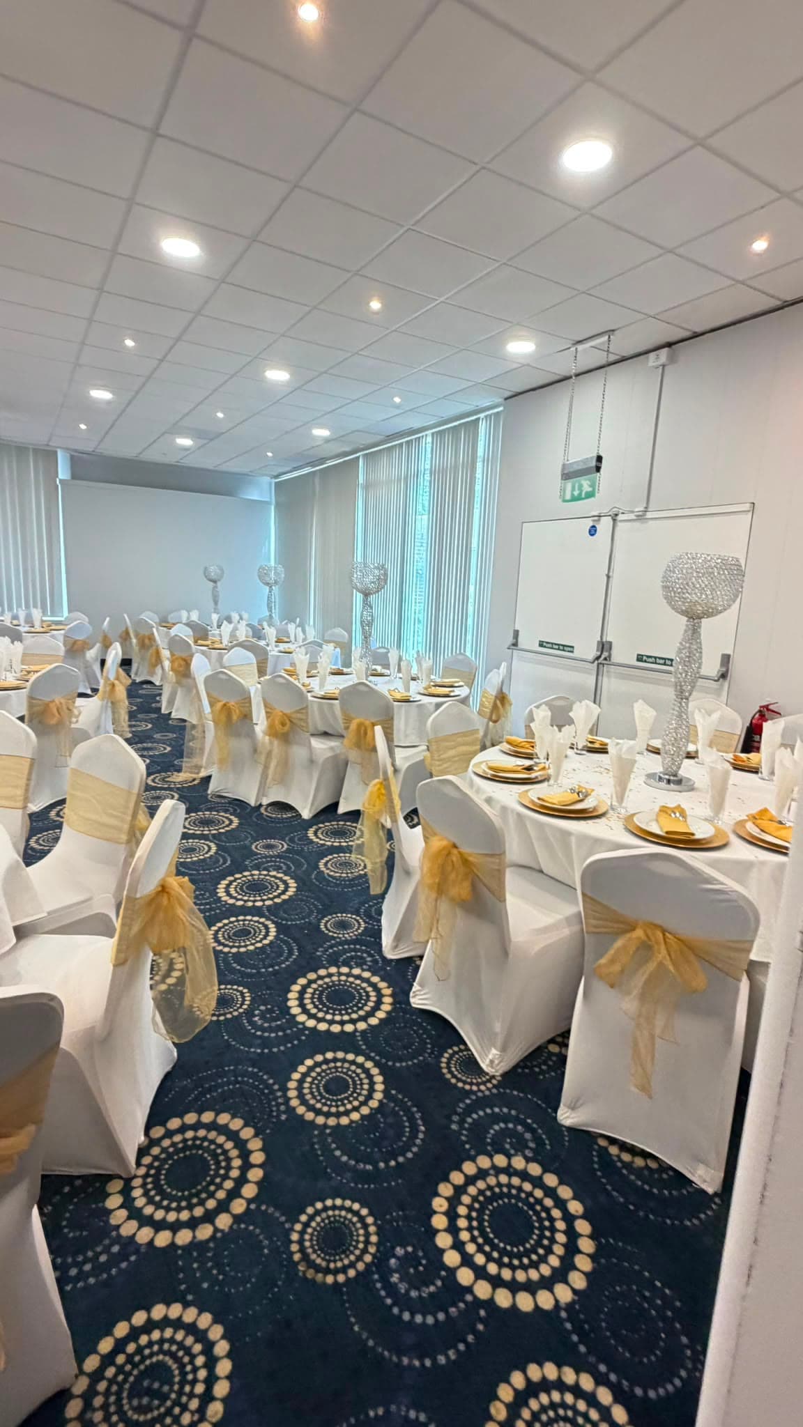 Close view of a laid table, gold organza chair sashes and place settings for ten.
